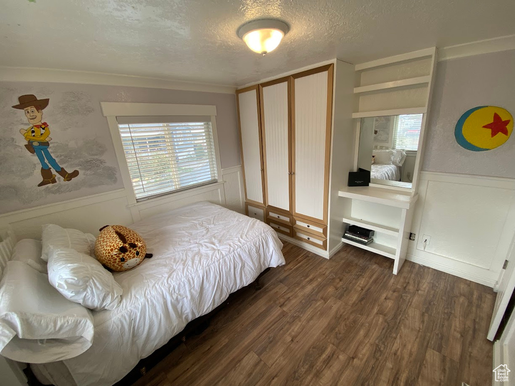 Bedroom with a textured ceiling, dark hardwood / wood-style floors, and multiple windows