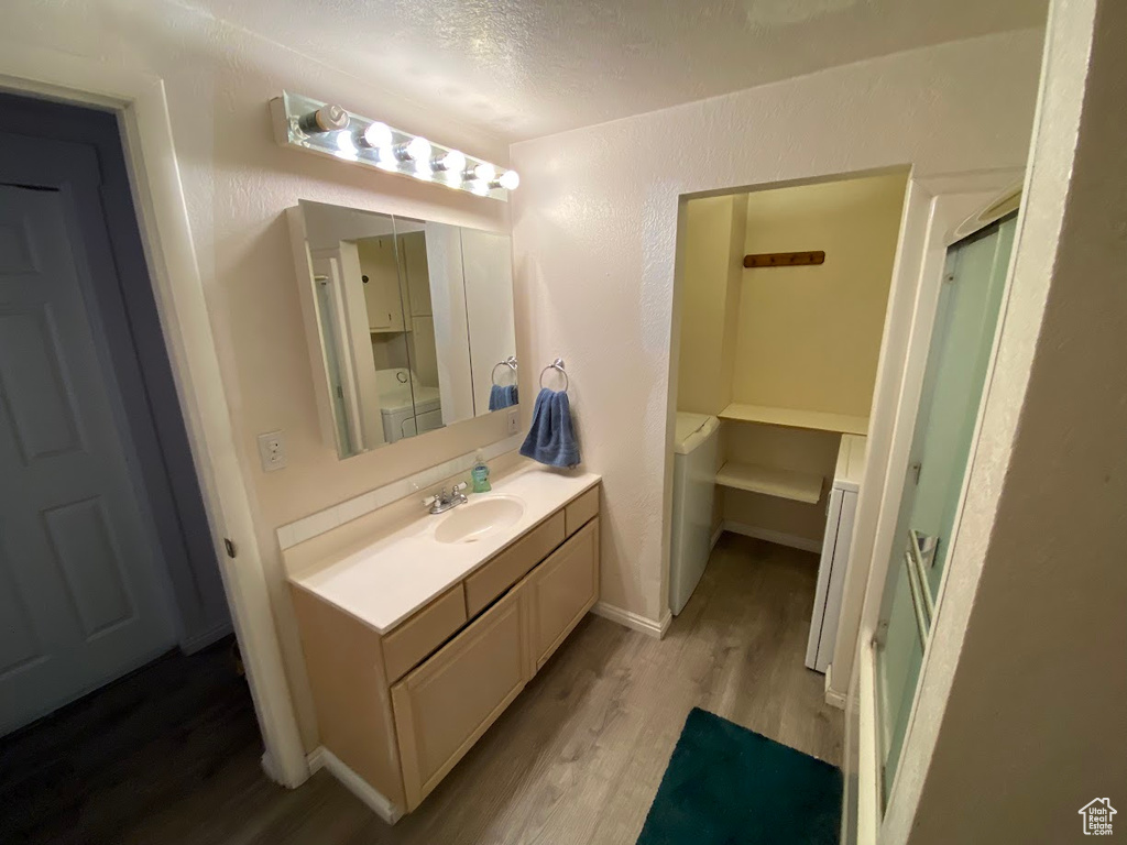 Bathroom featuring separate washer and dryer, wood-type flooring, an enclosed shower, a textured ceiling, and vanity