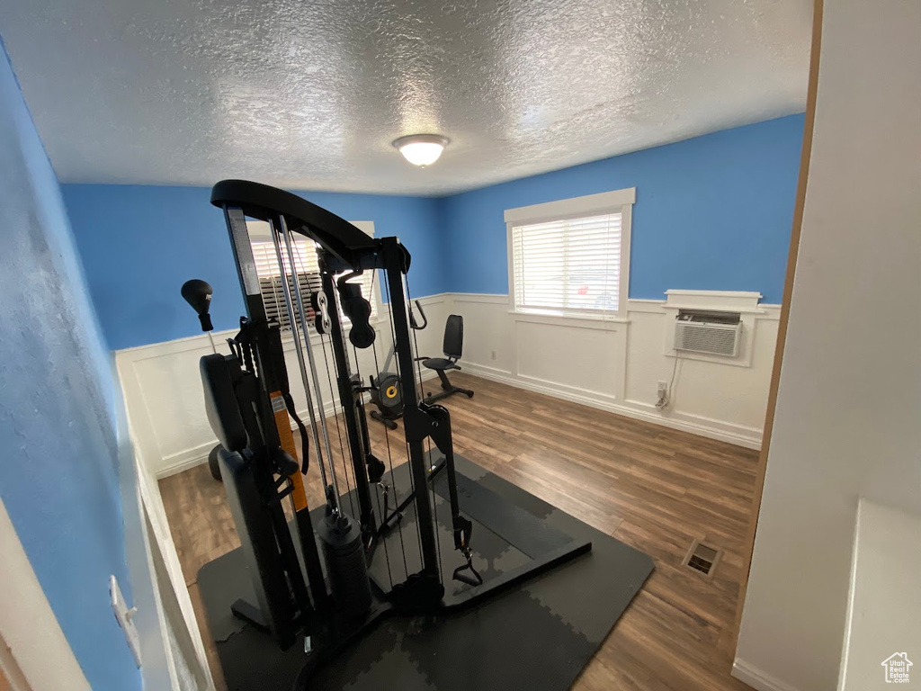 Workout area with dark hardwood / wood-style floors, a textured ceiling, and a wall mounted AC