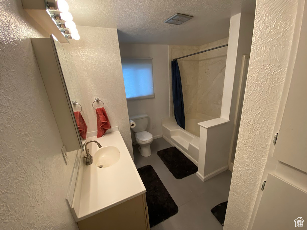 Full bathroom with vanity, toilet, a textured ceiling, and shower / tub combo