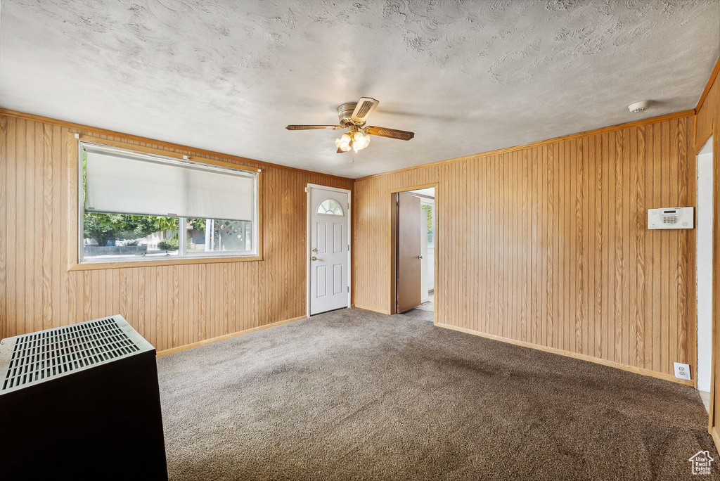 Interior space featuring wooden walls, a textured ceiling, and ceiling fan