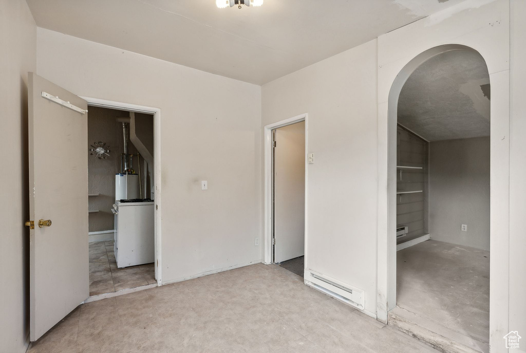 Unfurnished bedroom featuring a baseboard heating unit and gas water heater