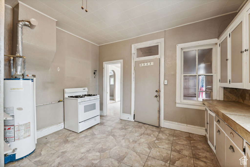 Kitchen with white gas range oven, gas water heater, and light tile patterned floors