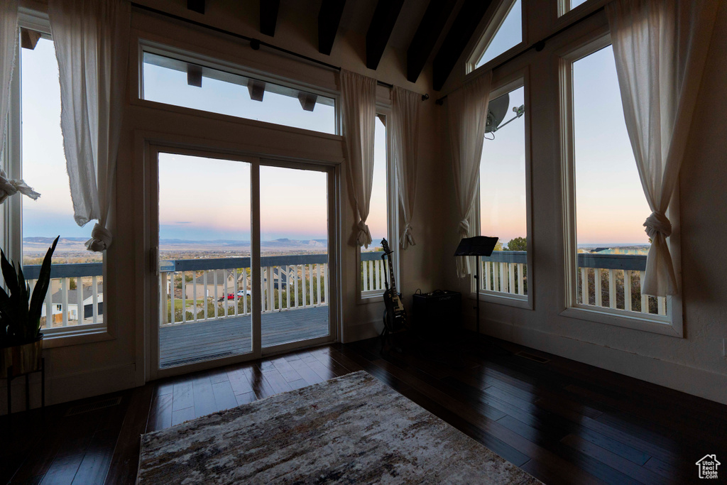 Spare room with a wealth of natural light and dark wood-type flooring