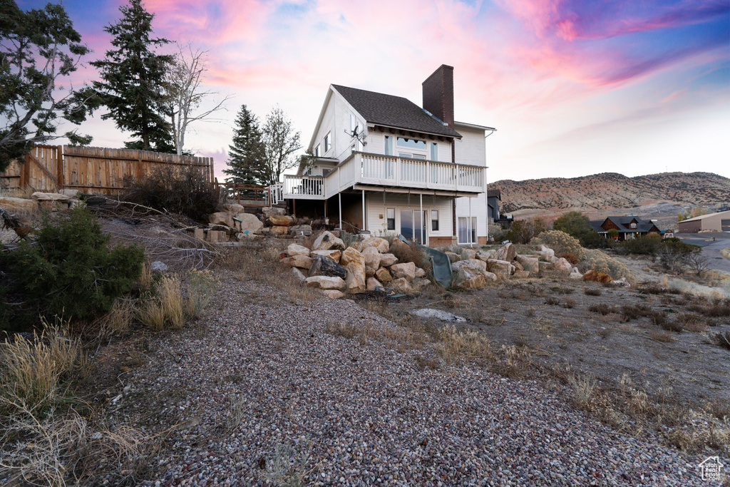 Back house at dusk featuring a deck with mountain view