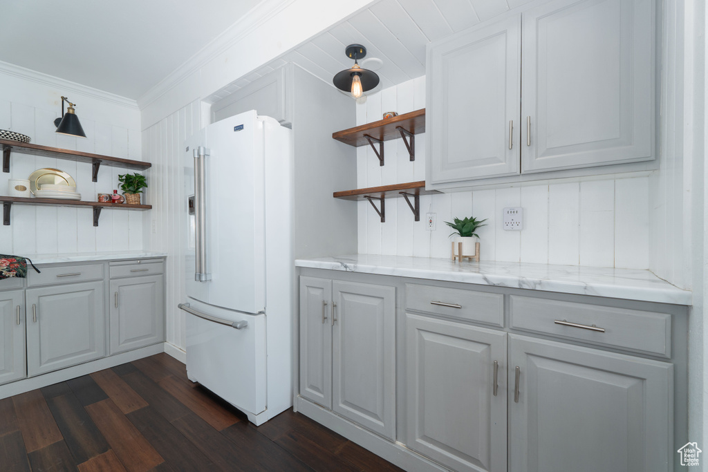 Kitchen featuring light stone countertops, dark hardwood / wood-style floors, crown molding, gray cabinets, and high end fridge