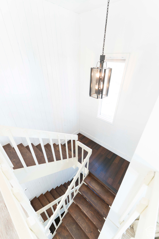 Stairway featuring wood-type flooring and an inviting chandelier