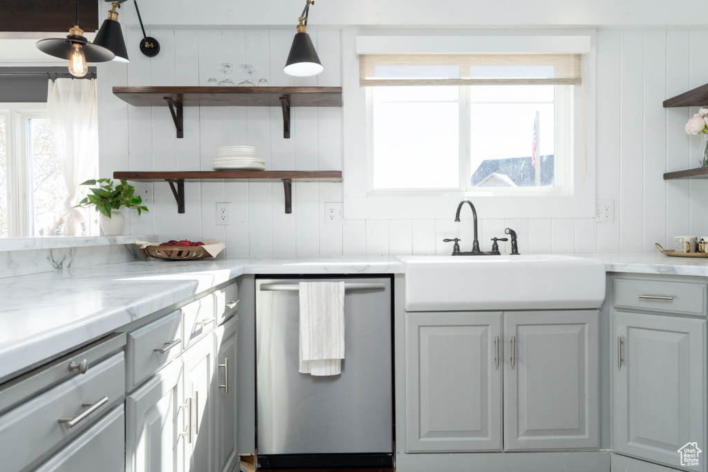 Kitchen with gray cabinetry, dishwasher, light stone countertops, and decorative light fixtures