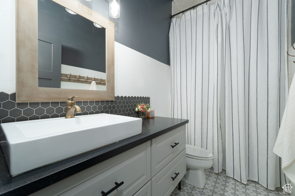 Bathroom with vanity, tasteful backsplash, toilet, and curtained shower