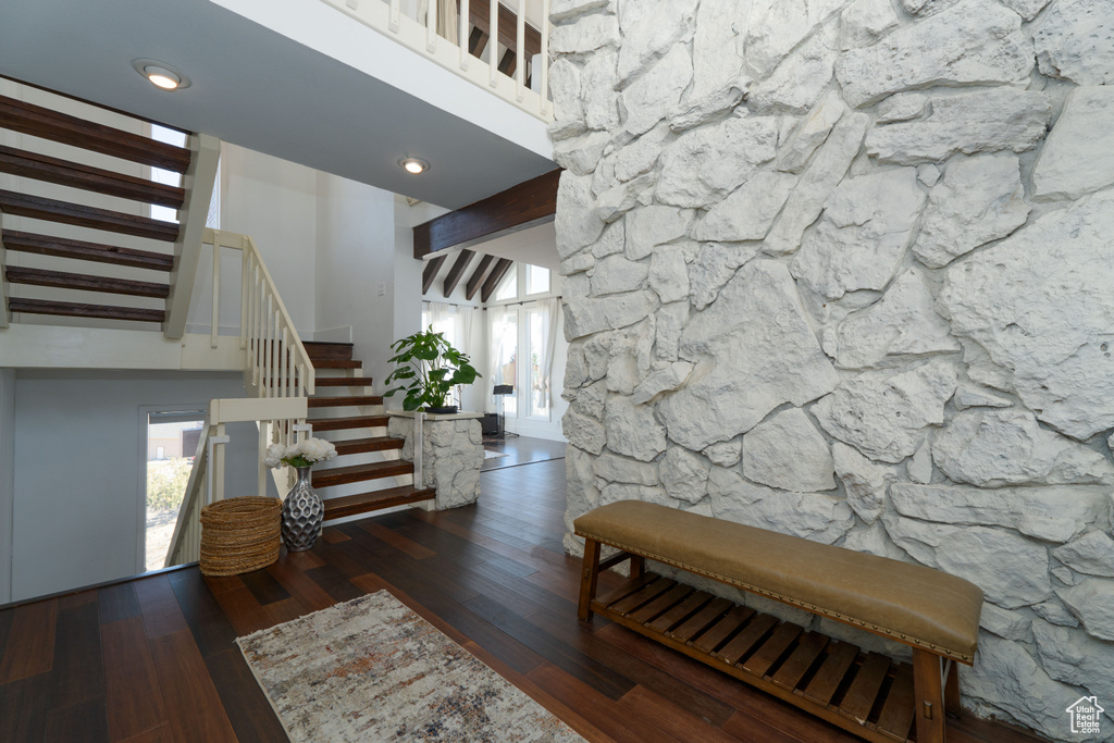 Interior space with beam ceiling, dark hardwood / wood-style flooring, and a high ceiling