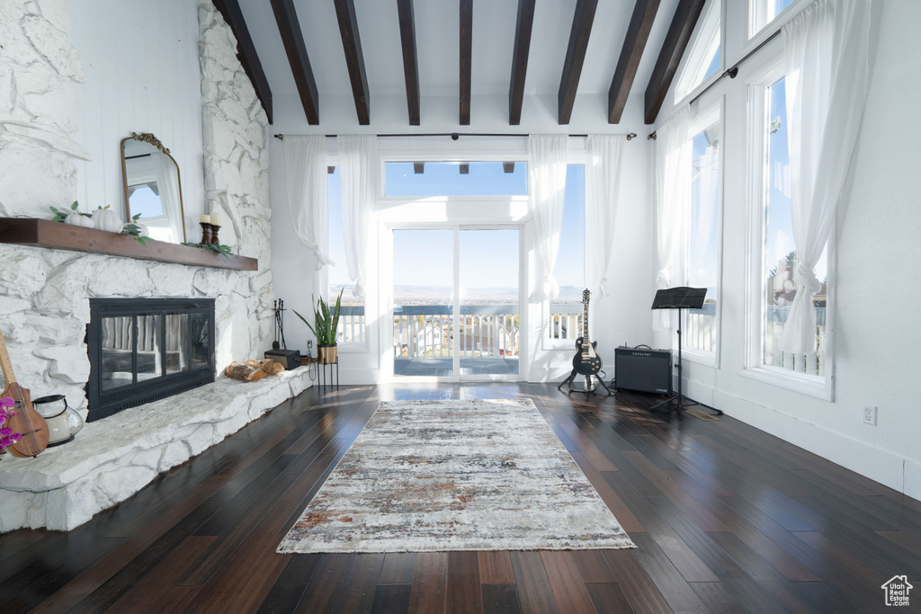 Living room with dark hardwood / wood-style floors, beam ceiling, a fireplace, and high vaulted ceiling