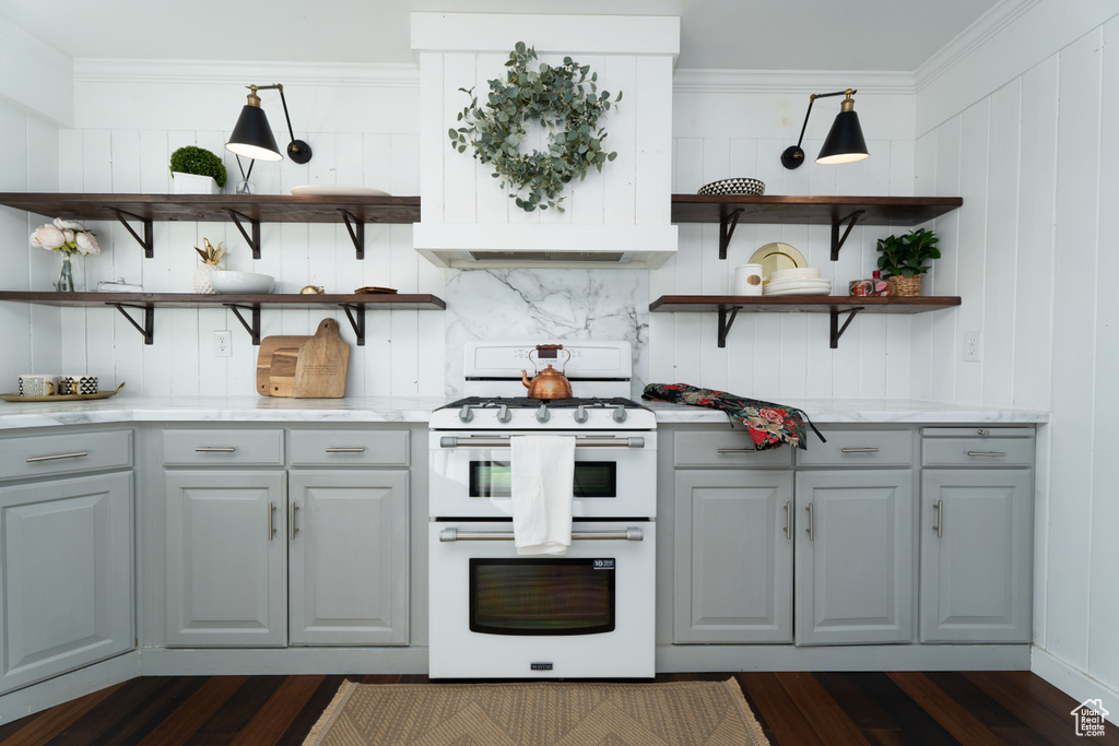 Kitchen with dark hardwood / wood-style flooring, ornamental molding, white range oven, gray cabinets, and wood walls