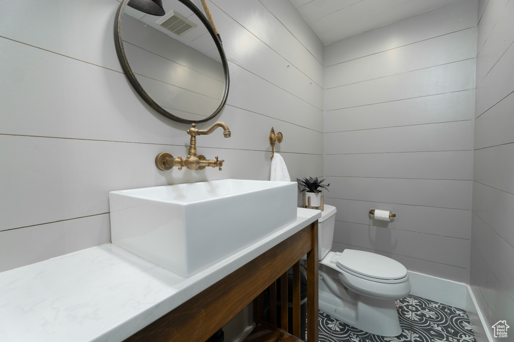 Bathroom featuring wooden walls, vanity, and toilet