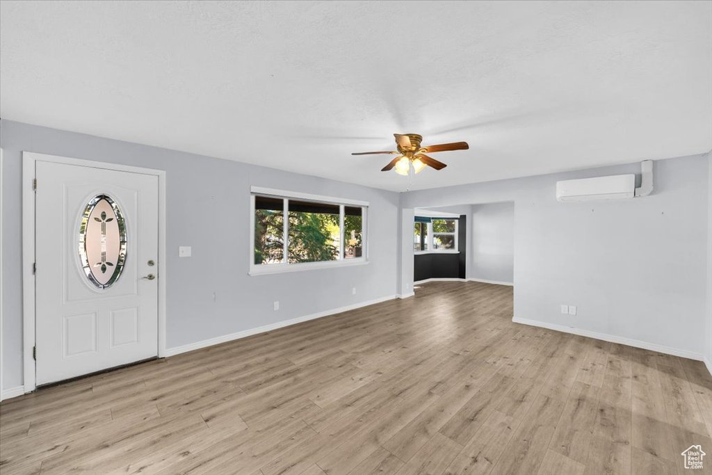 Entryway featuring a wall unit AC, light hardwood / wood-style flooring, and ceiling fan