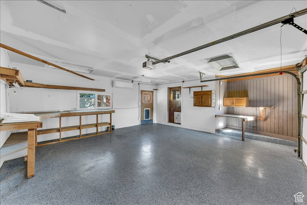 Garage featuring an AC wall unit and a garage door opener