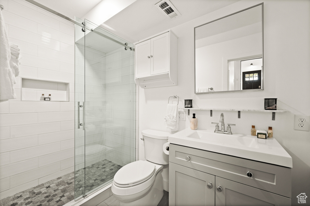 Bathroom with vanity, a shower with shower door, and toilet