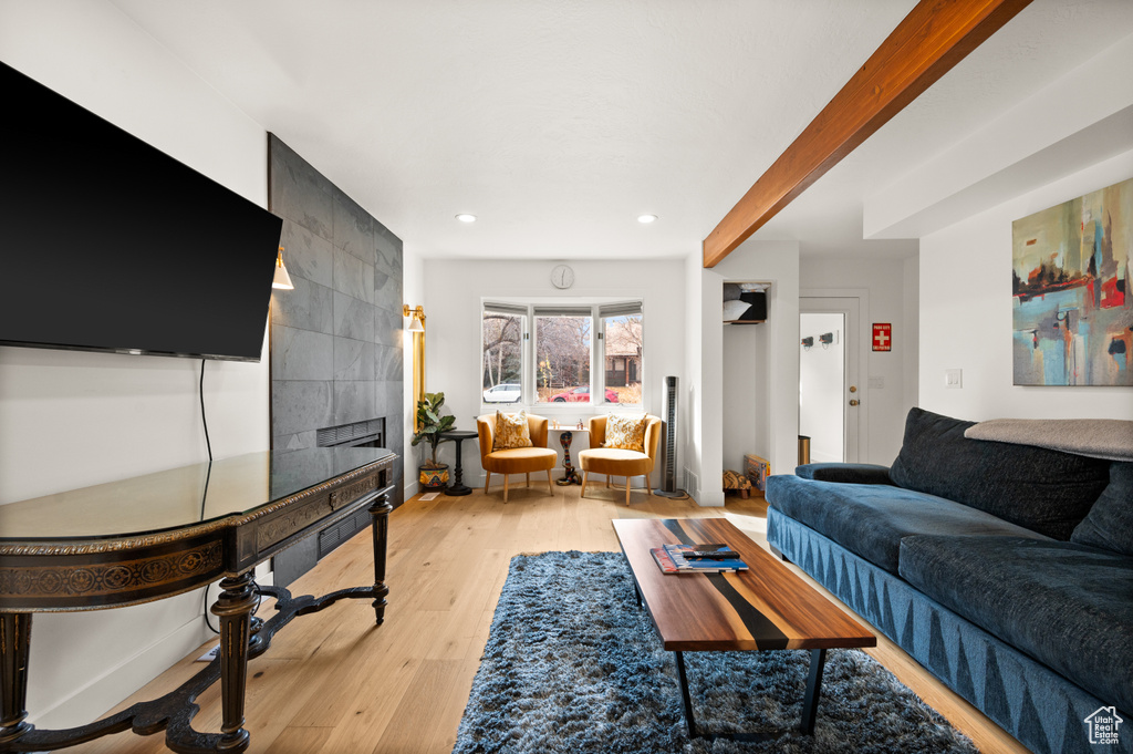 Living room featuring beam ceiling, a fireplace, and light hardwood / wood-style floors