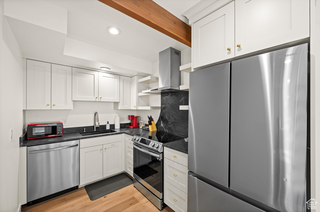 Kitchen featuring white cabinetry, sink, stainless steel appliances, and ventilation hood