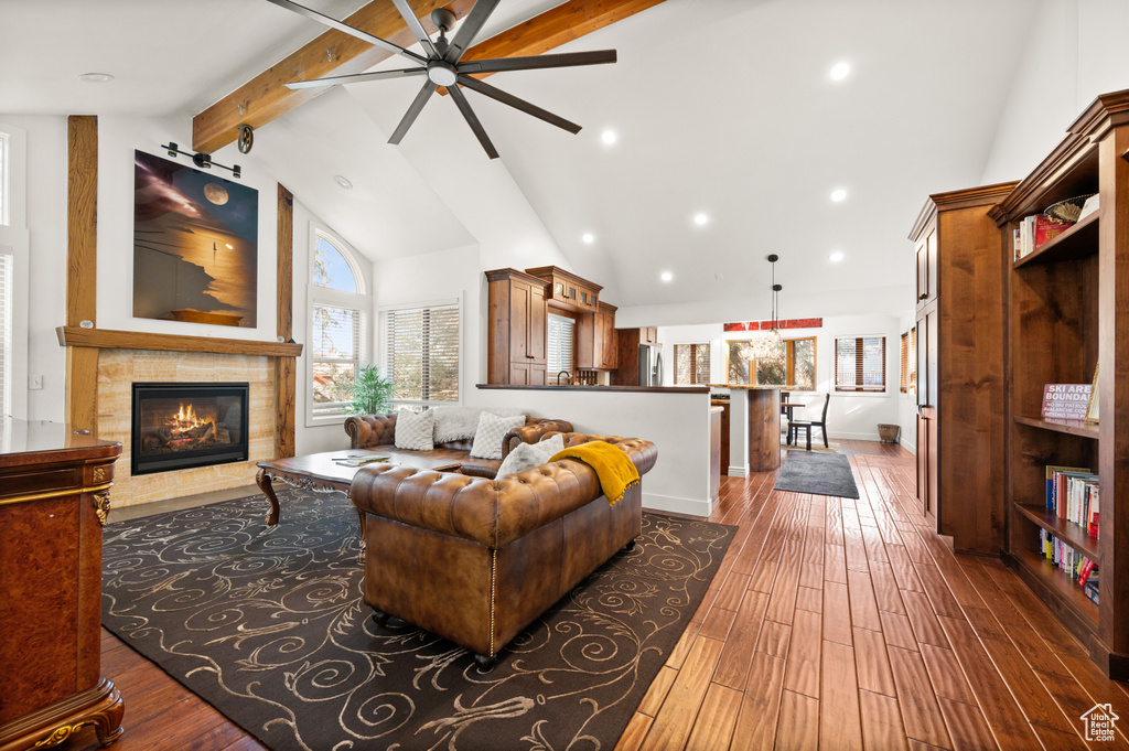 Living room with beamed ceiling, dark hardwood / wood-style floors, a fireplace, and ceiling fan