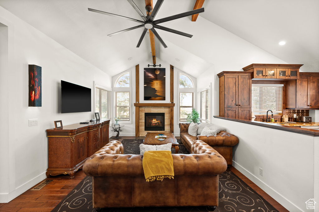 Living room with dark hardwood / wood-style flooring, ceiling fan, sink, a fireplace, and vaulted ceiling with beams