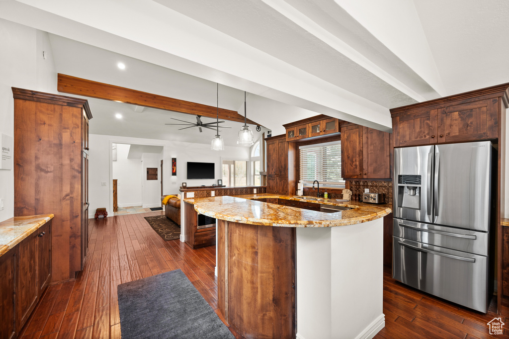 Kitchen featuring light stone countertops, hanging light fixtures, dark hardwood / wood-style floors, and stainless steel refrigerator with ice dispenser