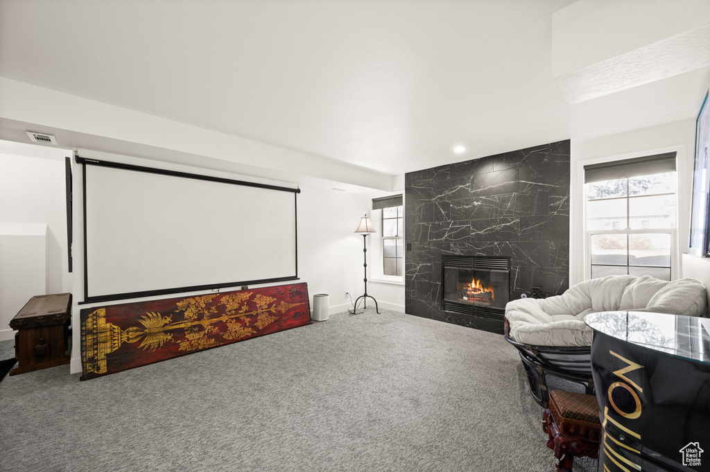 Carpeted home theater featuring a large fireplace