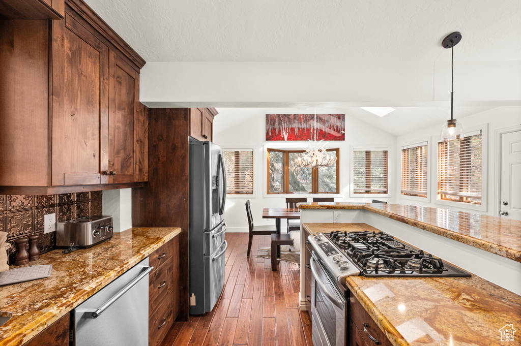 Kitchen with pendant lighting, dark hardwood / wood-style flooring, a healthy amount of sunlight, and appliances with stainless steel finishes