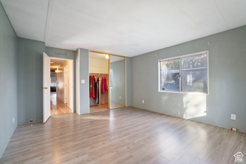 Unfurnished bedroom featuring a walk in closet, light hardwood / wood-style floors, and a closet