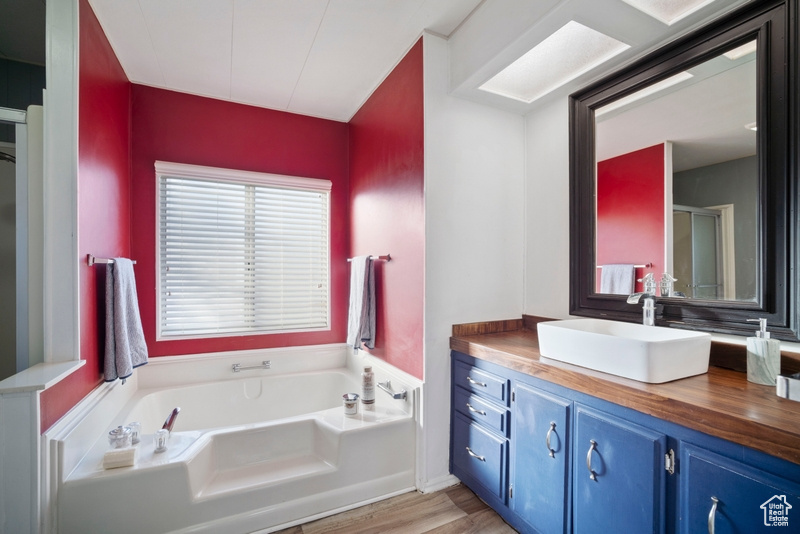 Bathroom with a bath, vanity, and wood-type flooring
