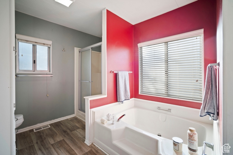 Bathroom with hardwood / wood-style flooring, toilet, and independent shower and bath