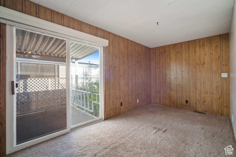 Carpeted empty room featuring wood walls