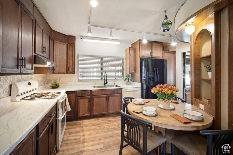 Kitchen with sink, light hardwood / wood-style flooring, pendant lighting, track lighting, and white appliances