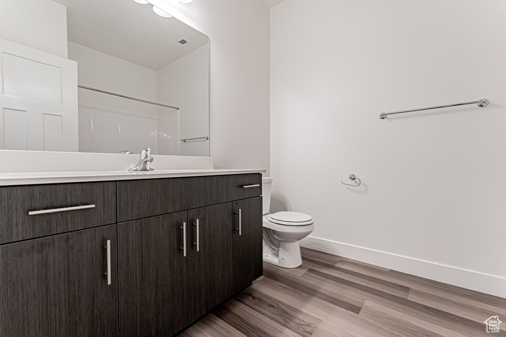 Bathroom featuring vanity, wood finished floors, toilet, and baseboards