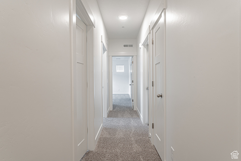 Hall with light colored carpet and baseboards