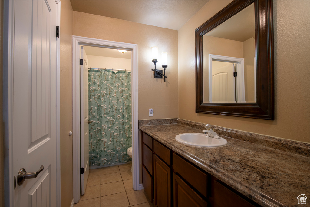 Bathroom featuring tile patterned flooring, a shower with curtain, vanity, and toilet