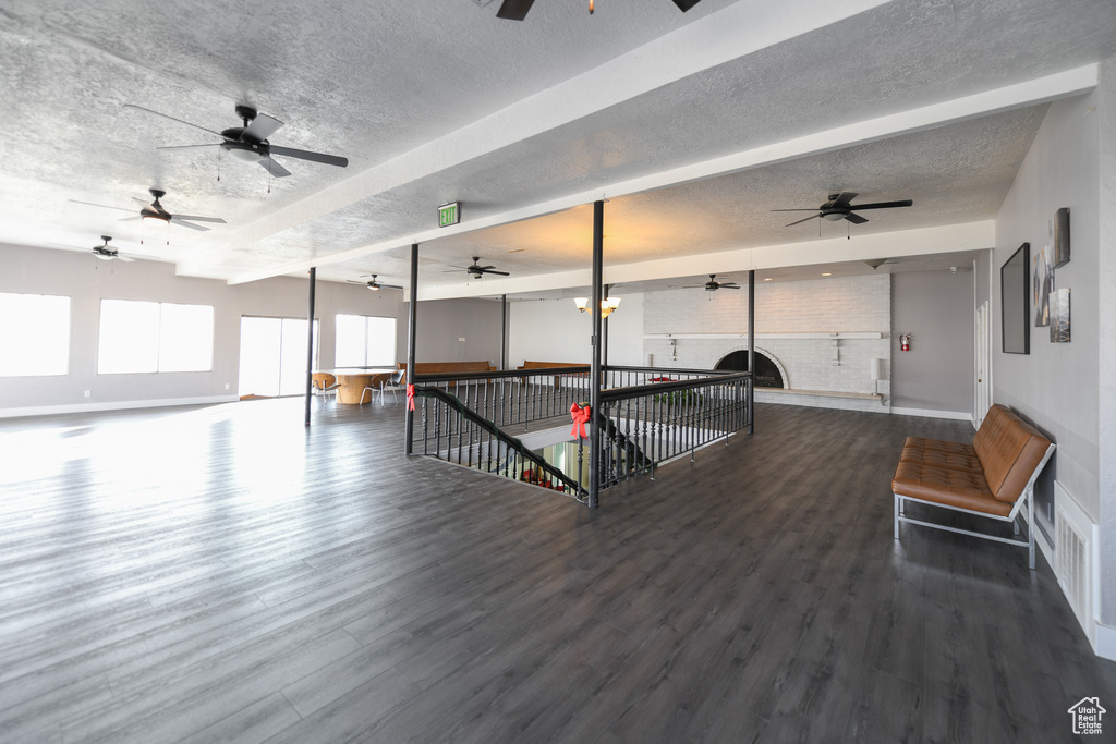 Recreation room with beamed ceiling, a textured ceiling, and hardwood / wood-style flooring