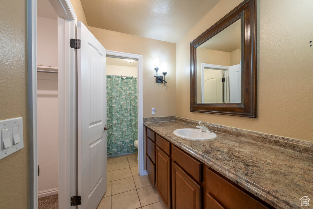 Bathroom with tile patterned floors, toilet, vanity, and a shower with shower curtain