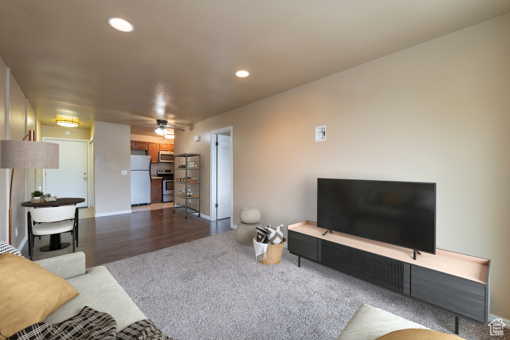 Living room featuring ceiling fan and dark wood-type flooring