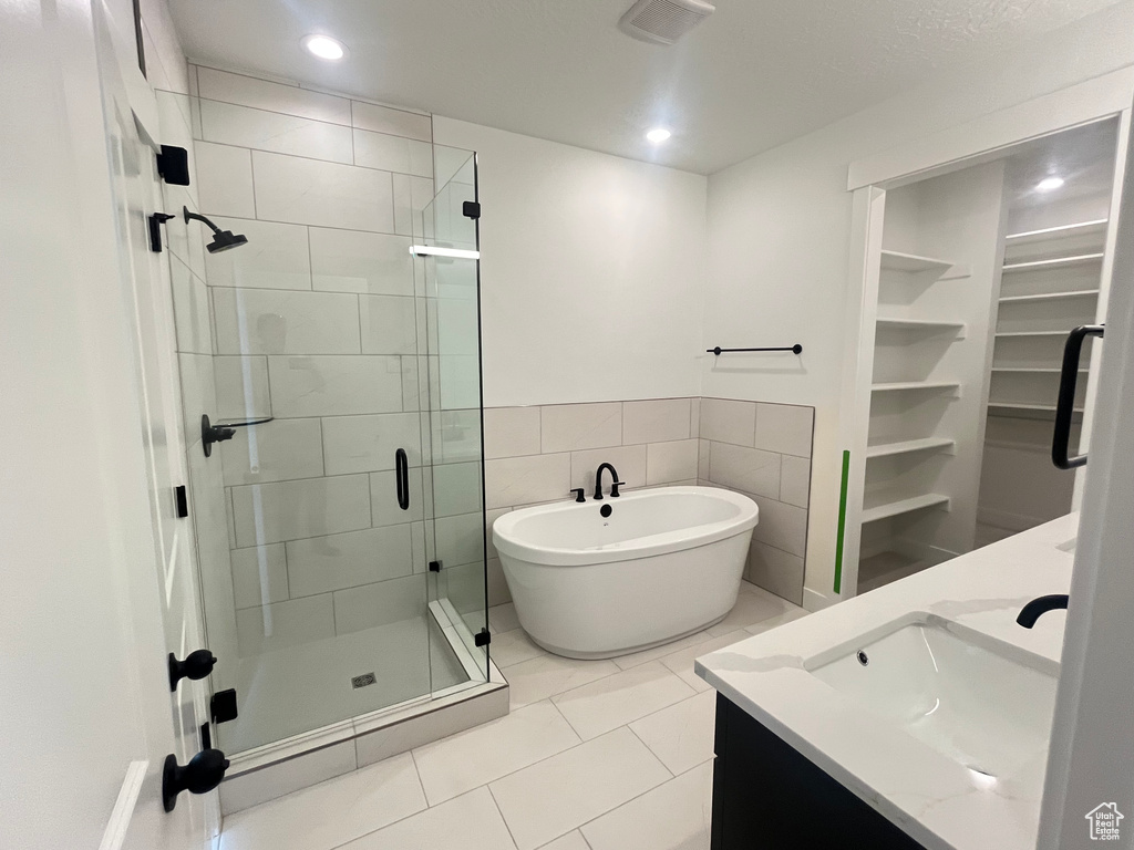 Bathroom featuring a freestanding bath, a sink, a spacious closet, a shower stall, and double vanity