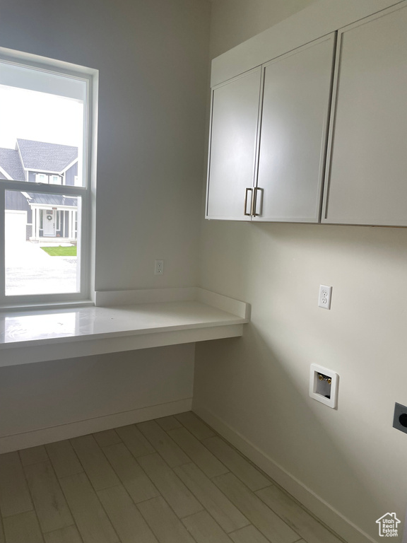 Washroom with cabinet space, hookup for an electric dryer, hookup for a washing machine, and baseboards