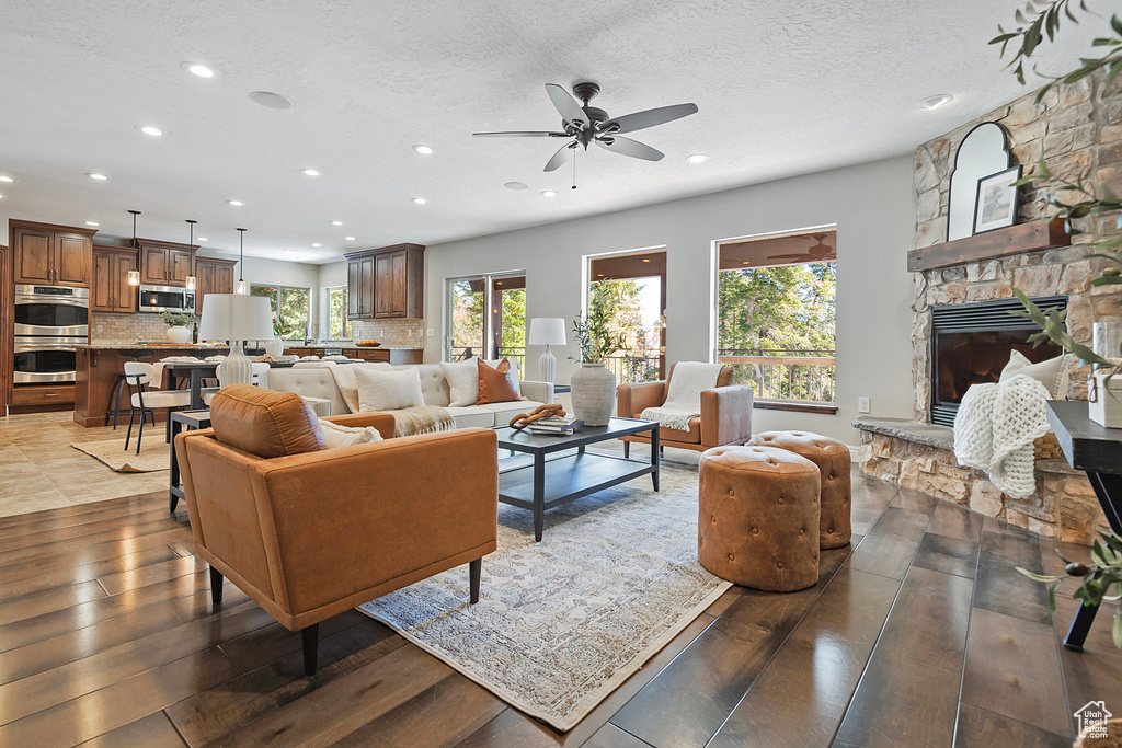 Living room with a fireplace, a textured ceiling, dark hardwood / wood-style floors, and ceiling fan