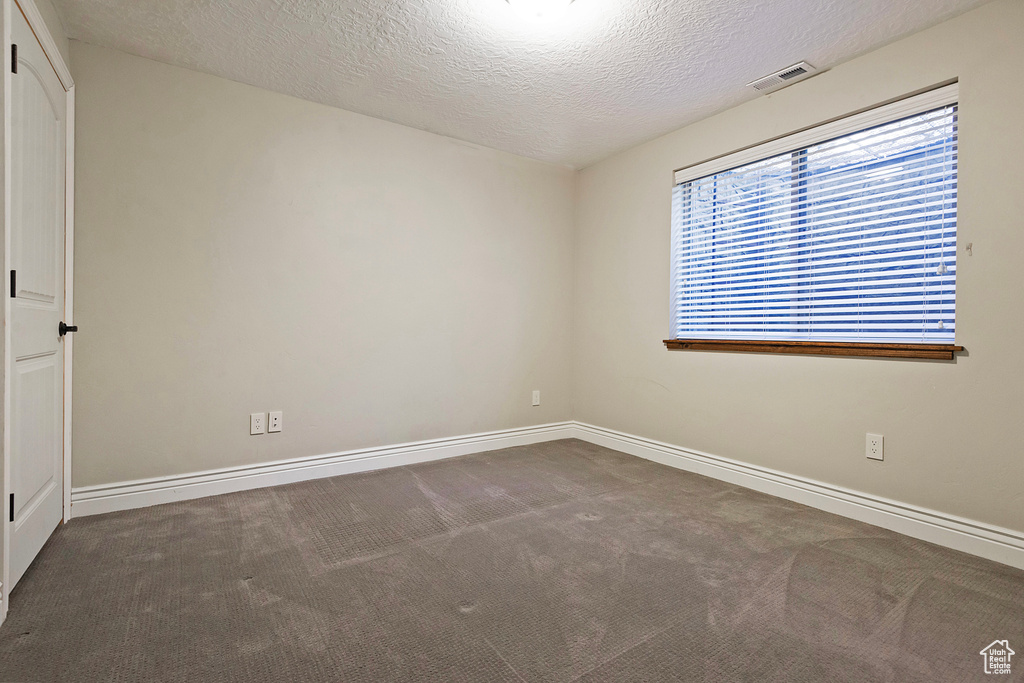 Spare room with a textured ceiling and dark carpet