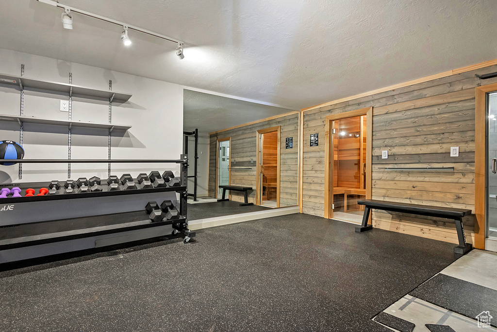 Workout area with wooden walls, rail lighting, and a textured ceiling