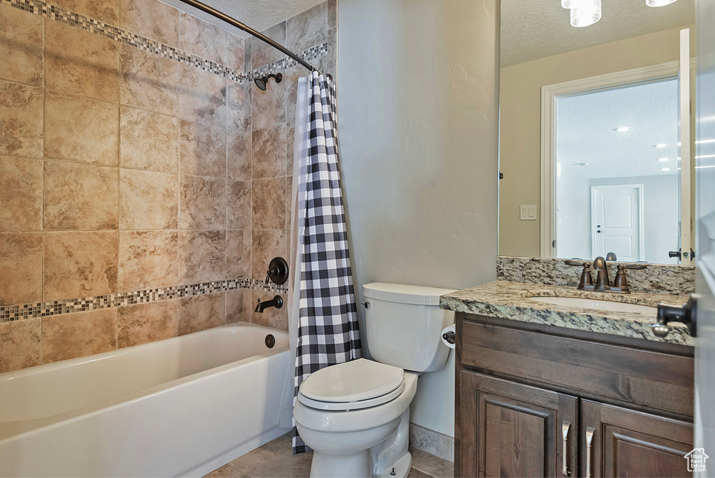 Full bathroom featuring shower / tub combo with curtain, vanity, a textured ceiling, and toilet