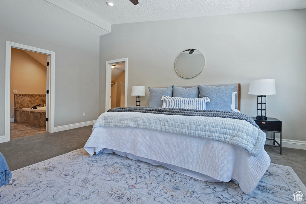 Bedroom featuring carpet floors, a textured ceiling, connected bathroom, and vaulted ceiling