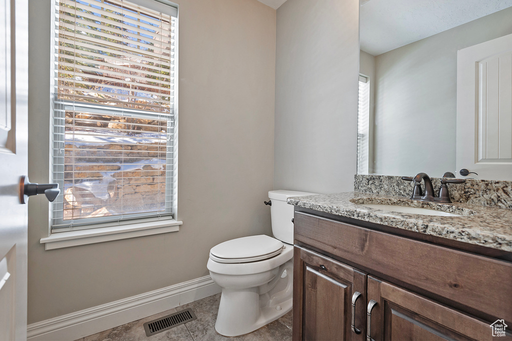 Bathroom featuring tile patterned floors, plenty of natural light, toilet, and vanity