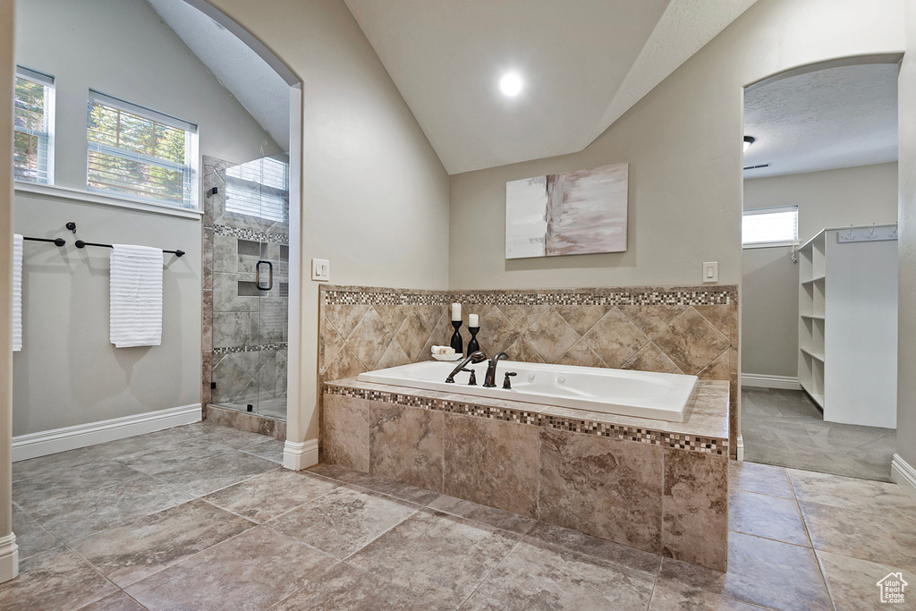 Bathroom featuring shower with separate bathtub, vaulted ceiling, and a healthy amount of sunlight