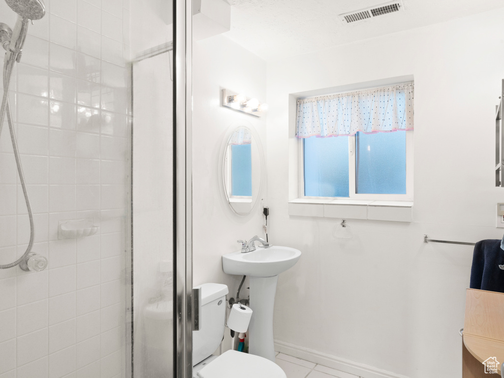 Bathroom featuring toilet, tile patterned flooring, and a shower with shower door