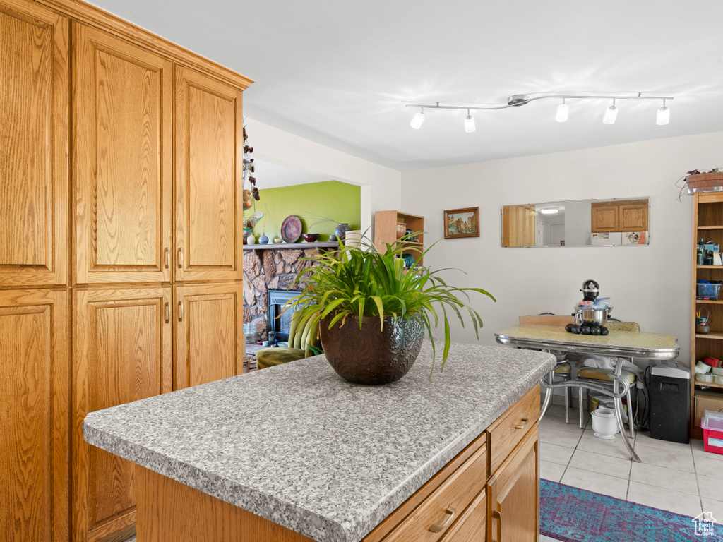 Kitchen featuring a stone fireplace, a kitchen island, track lighting, and light tile patterned floors