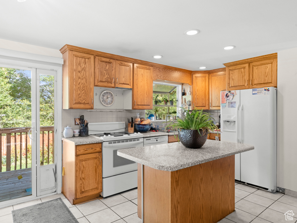 Kitchen with light tile patterned flooring, white appliances, backsplash, and a kitchen island